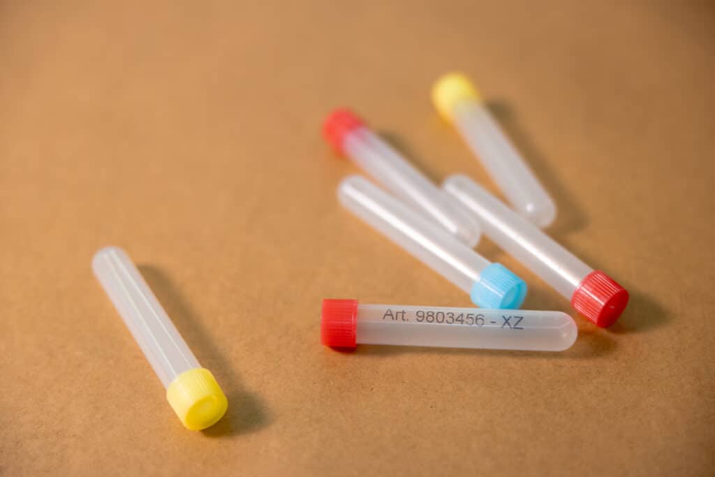 Varios tubos de plástico con tapones de colores y etiquetado impreso