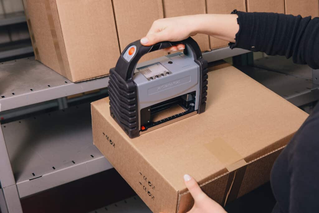 REINER jetStamp 1025 con funda protectora de silicona negra al imprimir sobre una caja de cartón