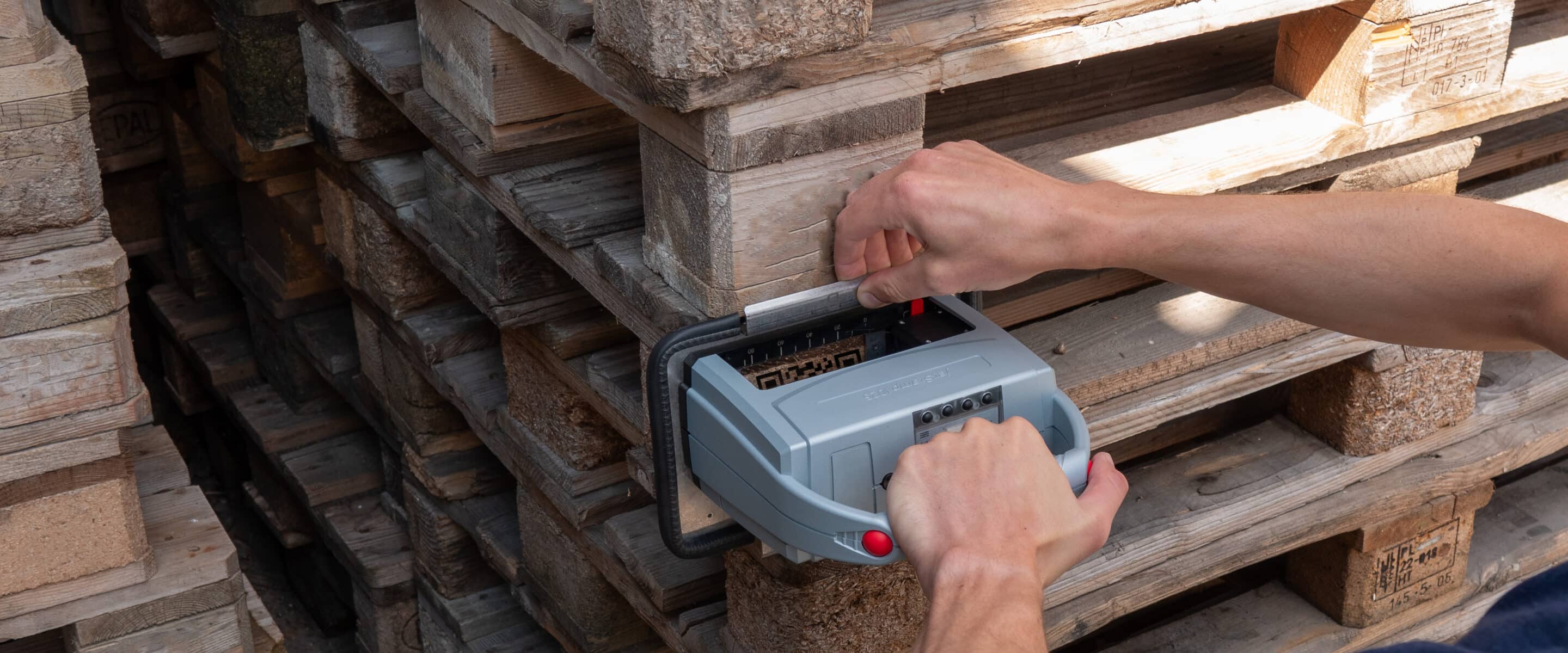 A person is marking stacked wooden pallets with the portable REINER jetStamp 1025.