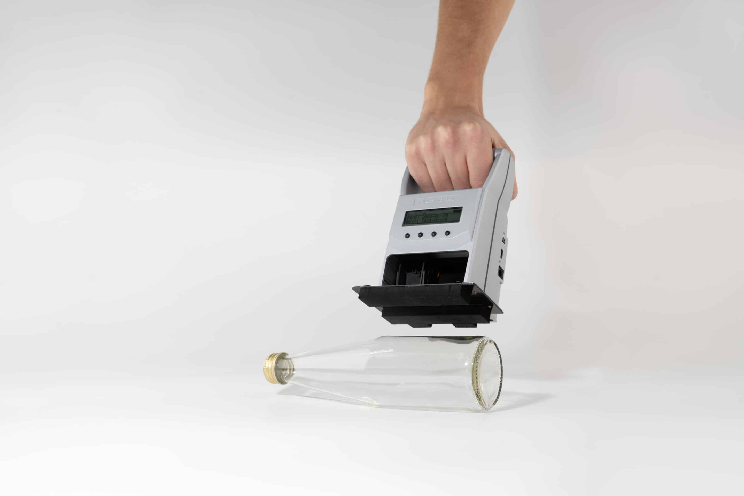 jetStamp 990 mit Positionierplatte über einer Glasflasche