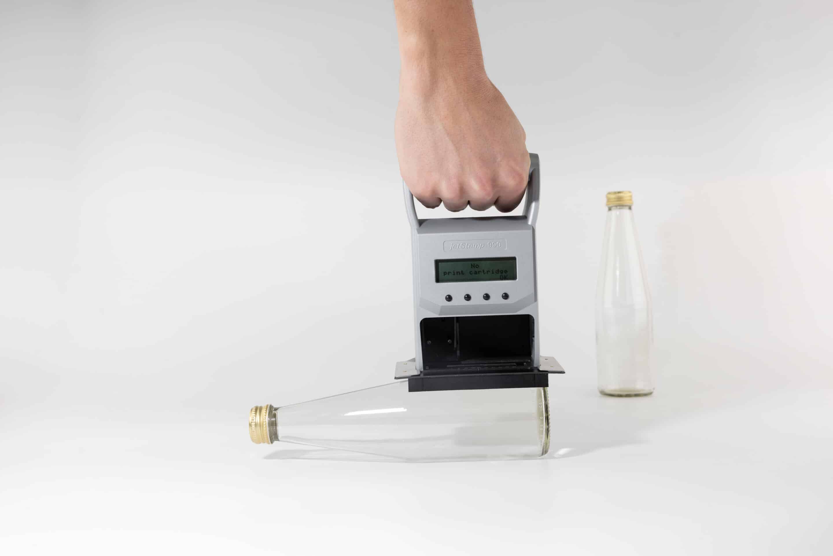 jetStamp 990 mit Positionierplatte über einer Glasflasche