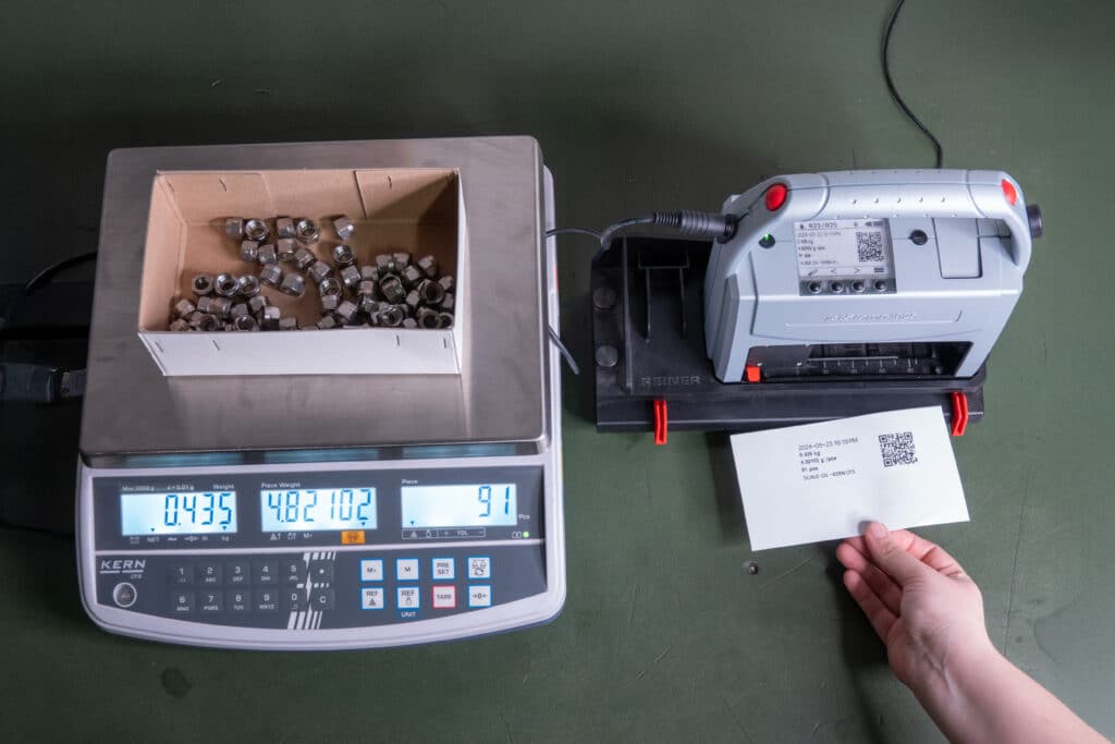 REINER jetStamp 1025 mit angeschlossenem V24-Sensorkabel neben einer Waage beim Bedrucken