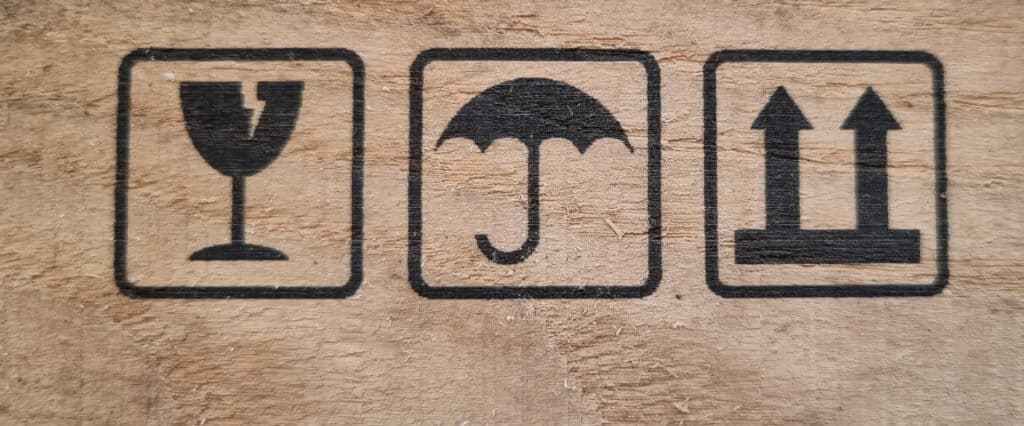 Shipping labels printed on wood indicating "Fragile," "Keep Dry," and "Transport Upright.".