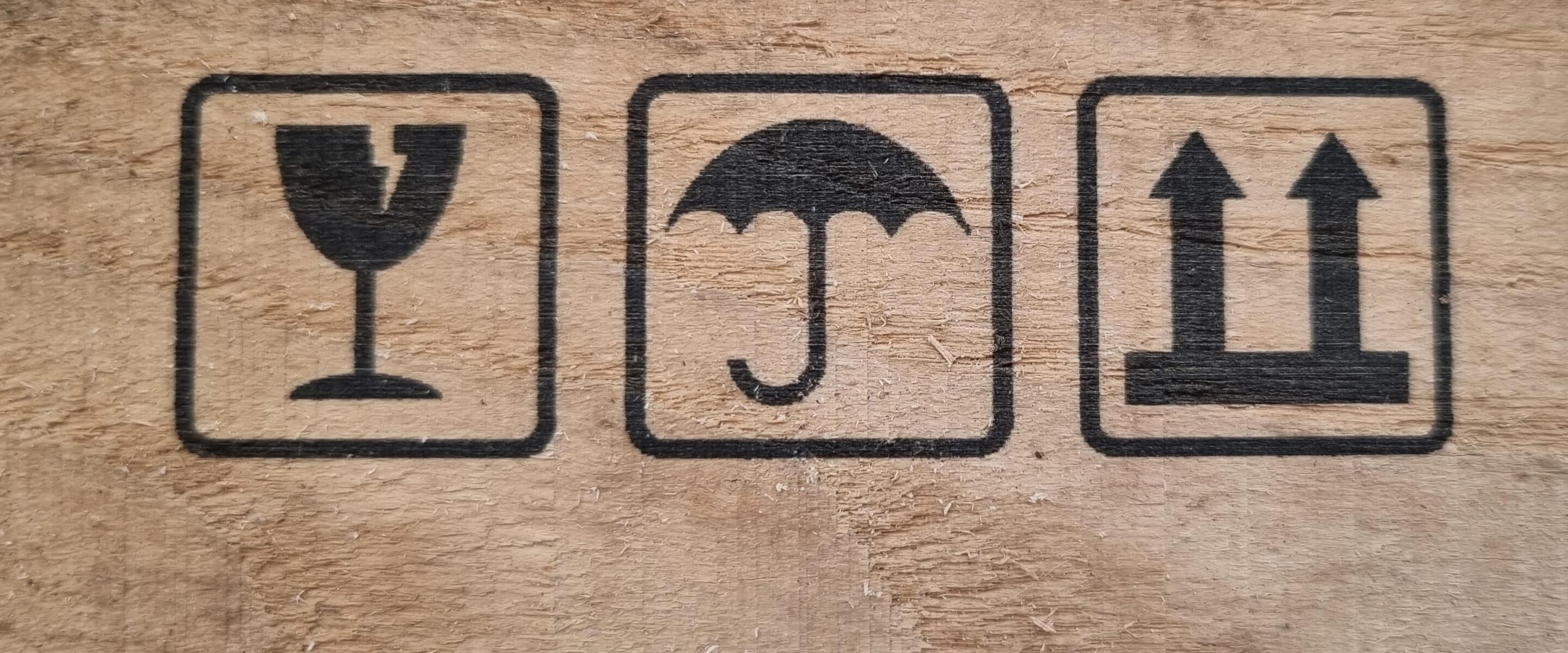 Shipping labels printed on wood indicating "Fragile," "Keep Dry," and "Transport Upright.".